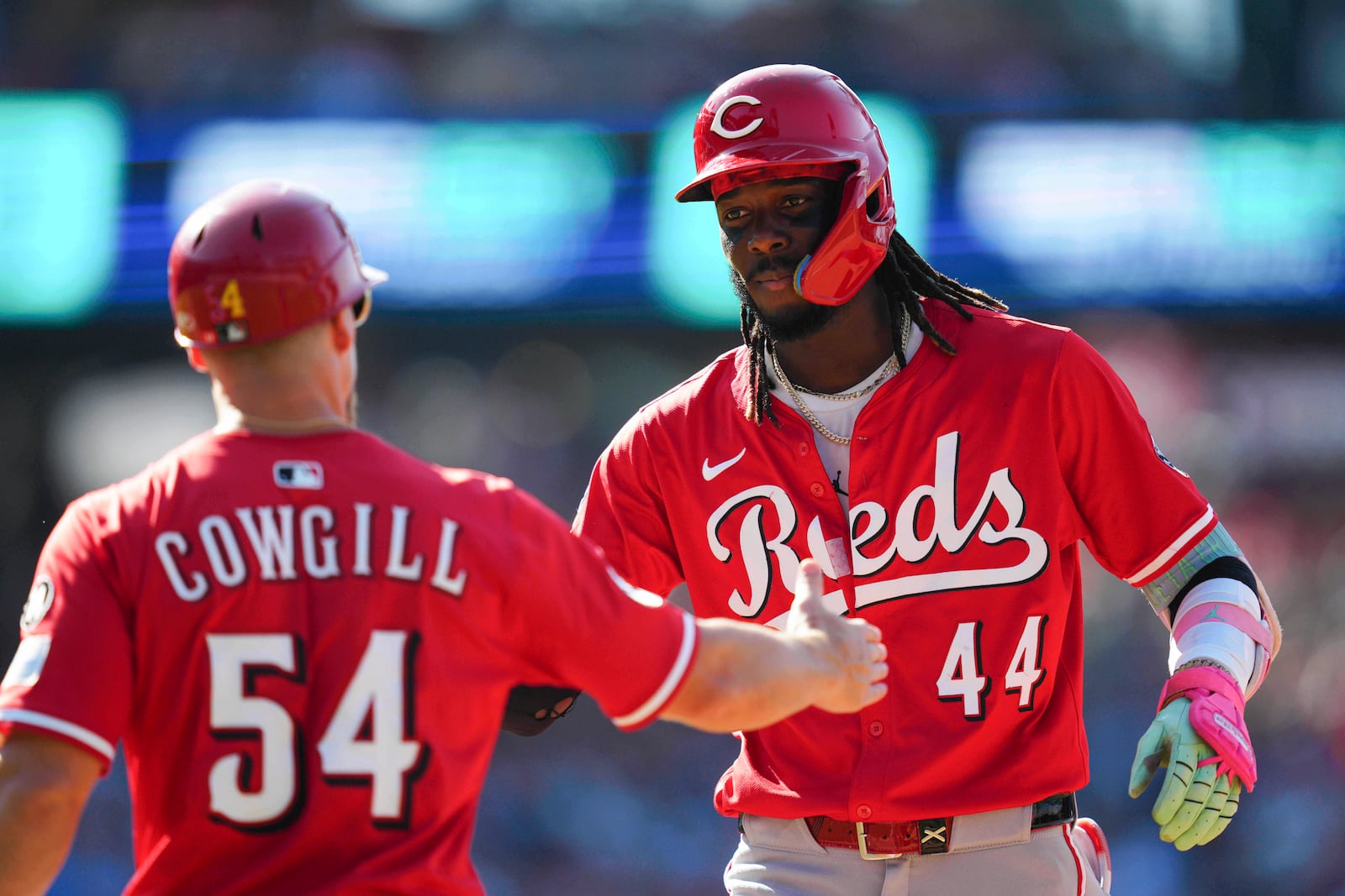 Cincinnati Reds' Elly De La Cruz (44) high-fives first base coach Collin Cowgill (54) after hitting a single during the fifth inning of a baseball game against the Philadelphia Phillies, Saturday, July 5, 2025, in Philadelphia. (AP Photo/Derik Hamilton)