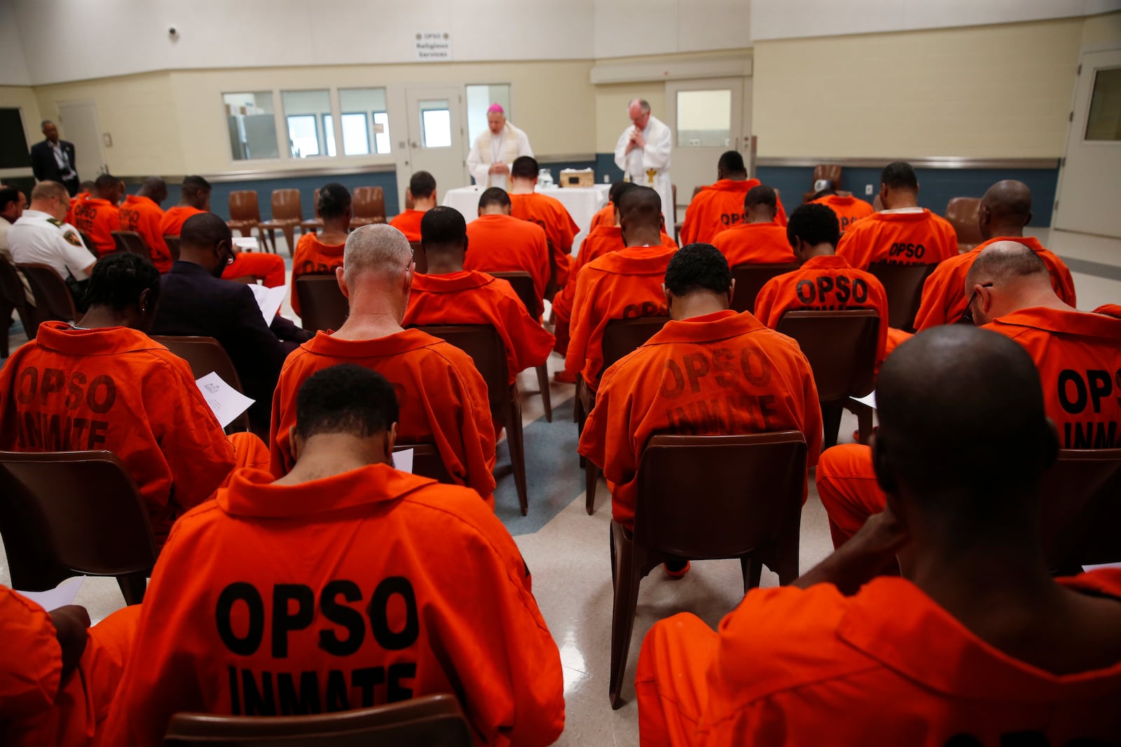 FILE - New Orleans Archbishop Gregory Aymond leads a Holy Thursday prayer service with Orleans Parish Prison Chaplain Father Terry Hayden, right, at the Orleans Justice Center in New Orleans on April 13, 2017. (AP Photo/Gerald Herbert, File)