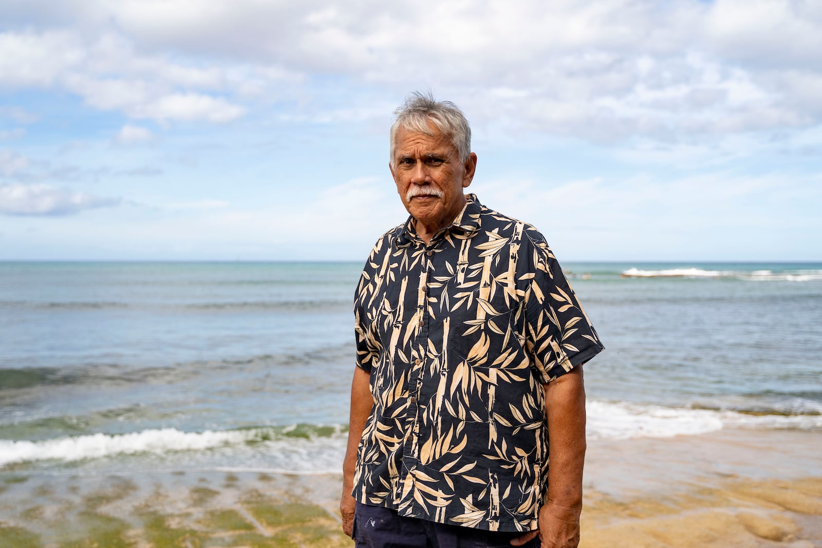 Cultural practitioner Glen Kila poses for a portrait near the shoreline where ancient petroglyphs at Pokai Bay, July 22, 2025, in Waianae, Hawaii. (AP Photo/Mengshin Lin)