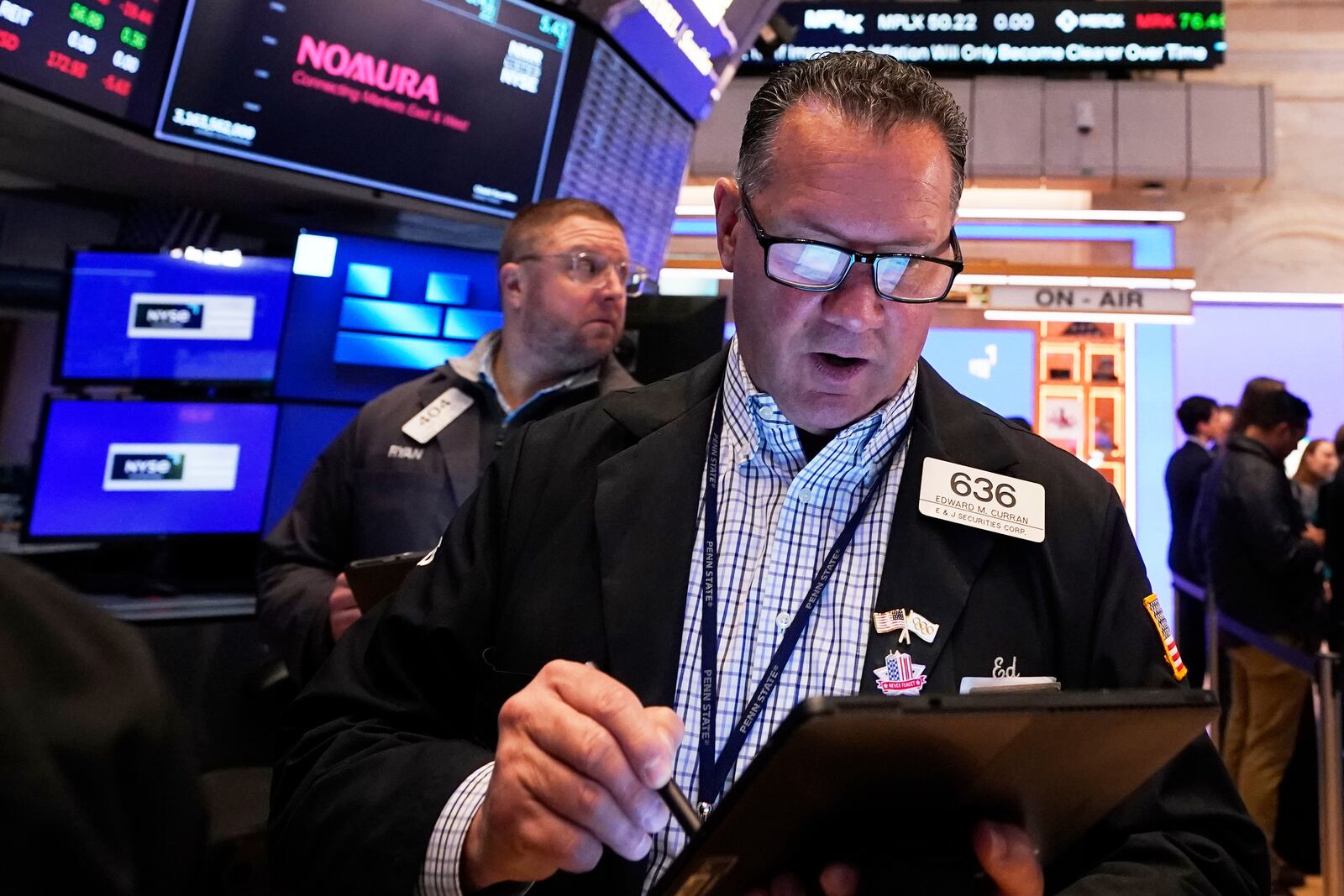 The handheld device of trader Edward Curran is reflected in his glasses as he works on the floor of the New York Stock Exchange, Thursday, April 17, 2025. (AP Photo/Richard Drew)
