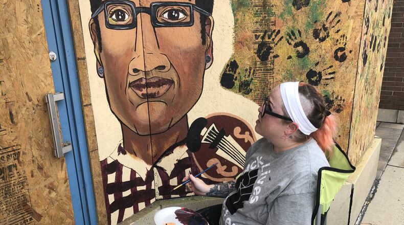 Artist Ashli Szymanski finishes a portrait of Elijah McClain on plywood outside a Middletown downtown business. The mural includes four portraits and Szymanski plans to add more. RICK McCRABB/STAFF