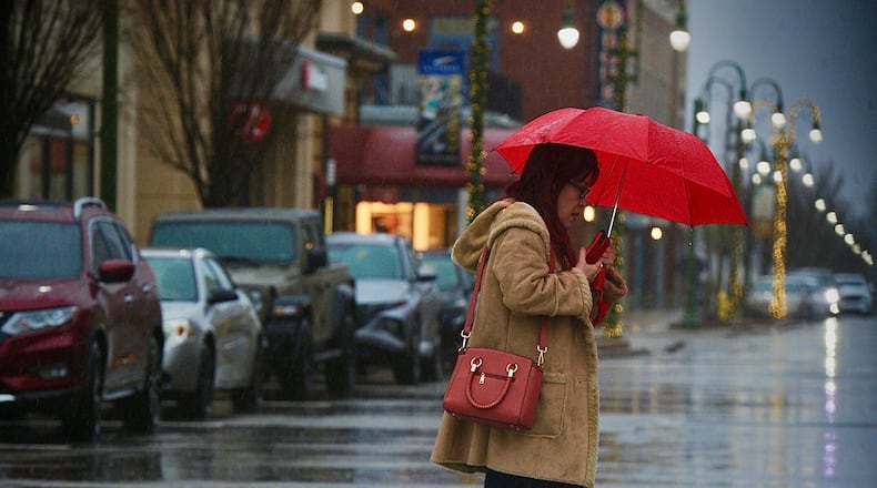 Rain and snow seems to be the recipe for the day, Tuesday, January 9, 2023 as this lady, uses an umbrella to do her shopping at the Greene Town Center. MARSHALL GORBY \STAFF