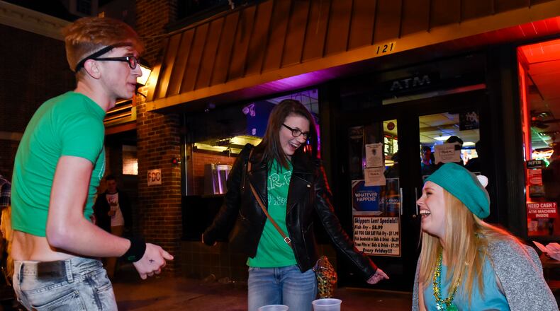 Jacob Rasmussen and Megan Kudej dance as Sidney Calicoat watches as they sit in front of Skippers before sunrise during Green Beer Day Thursday, March 19 in Oxford. NICK GRAHAM/ STAFF