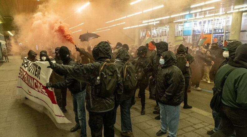 A protester holds a smoke torch during demonstration by the Collectif Désinvestir pour la Palestine and the Convergence des luttes anticapitalistes (CLAC) in Montreal Friday Nov. 22, 2024. The demonstration was in support of Palestine and in opposition to the meeting of NATO parliamentarians in Montreal.