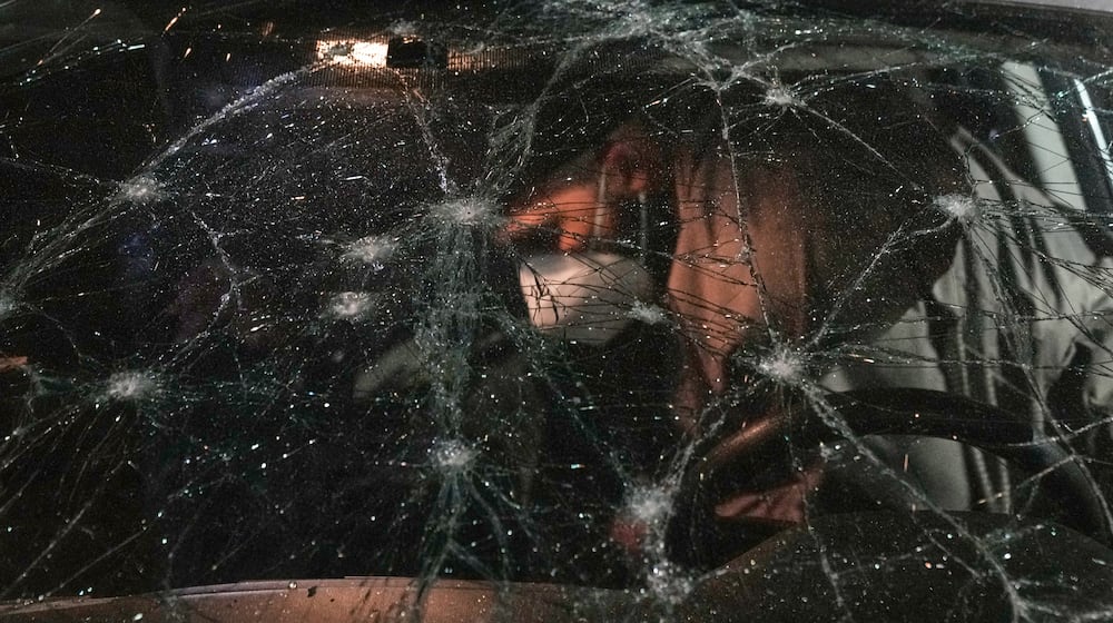 A man inspects a car damaged in an Israeli airstrike at the Ramlet al-Baida public beach in Beirut, Lebanon, early Thursday, March 12, 2026. (AP Photo/Bilal Hussein)