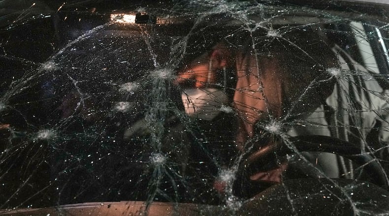 A man inspects a car damaged in an Israeli airstrike at the Ramlet al-Baida public beach in Beirut, Lebanon, early Thursday, March 12, 2026. (AP Photo/Bilal Hussein)