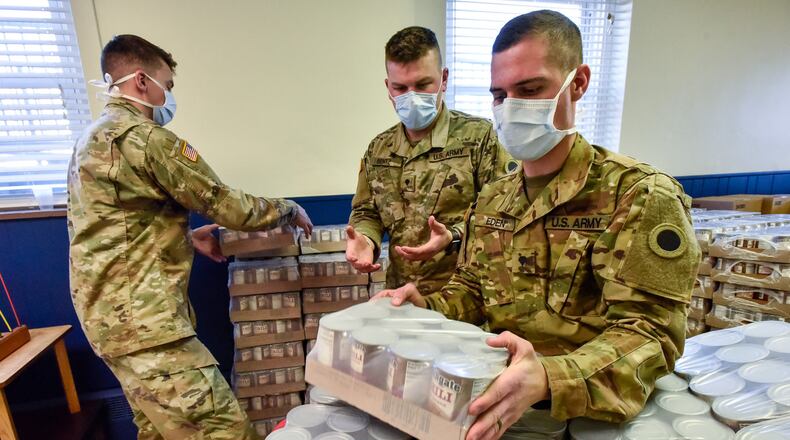 Spc. Aaron Carmack, left, Spc. Seth Bentz, middle, and Spc. Kyle Eden, right, with Ohio Army National Guard Delta Company 237th deliver food from Shared Harvest Food Bank to The Salvation Army on First Avenue in Middletown Tuesday, April 21, 2020. National Guard members have been activated around the area to help pack and distribute food during the coronavirus pandemic. The Salvation Army continues to serve food items and meals to those in need in the community with the help of their staff and volunteers. NICK GRAHAM / STAFF