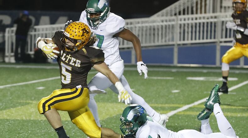 Alter’s Lane Harshbarger tries to avoid being tackled by Chaminade Julienne’s Isaiah Haywood and Brendan Kadel as he carries the ball during a Division III playoff game Nov. 3, 2017, at Fairmont. BILL LACKEY/STAFF