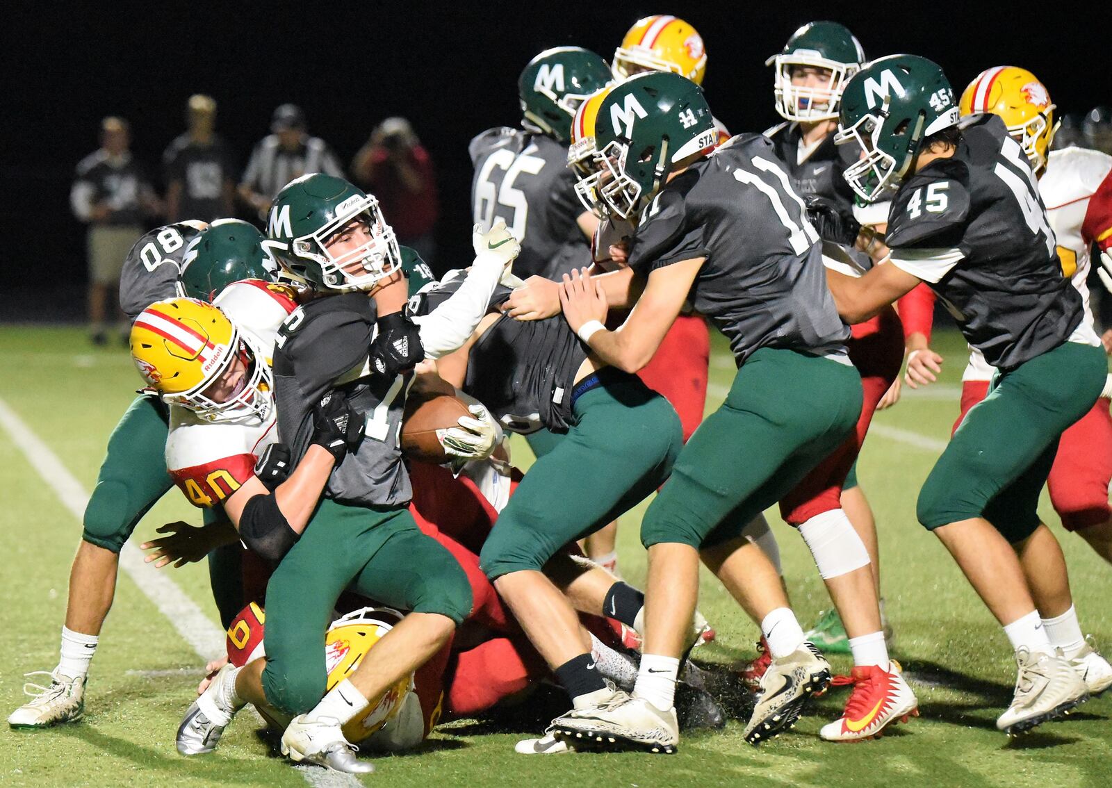 Fenwick’s Carter Earls (40) and Tyler Houck (19) are on the tackle of Jack Kamp (15) of McNicholas on Friday night at Penn Station Stadium in Cincinnati. Fenwick took a 57-26 win. CONTRIBUTED PHOTO BY ANGIE MOHRHAUS