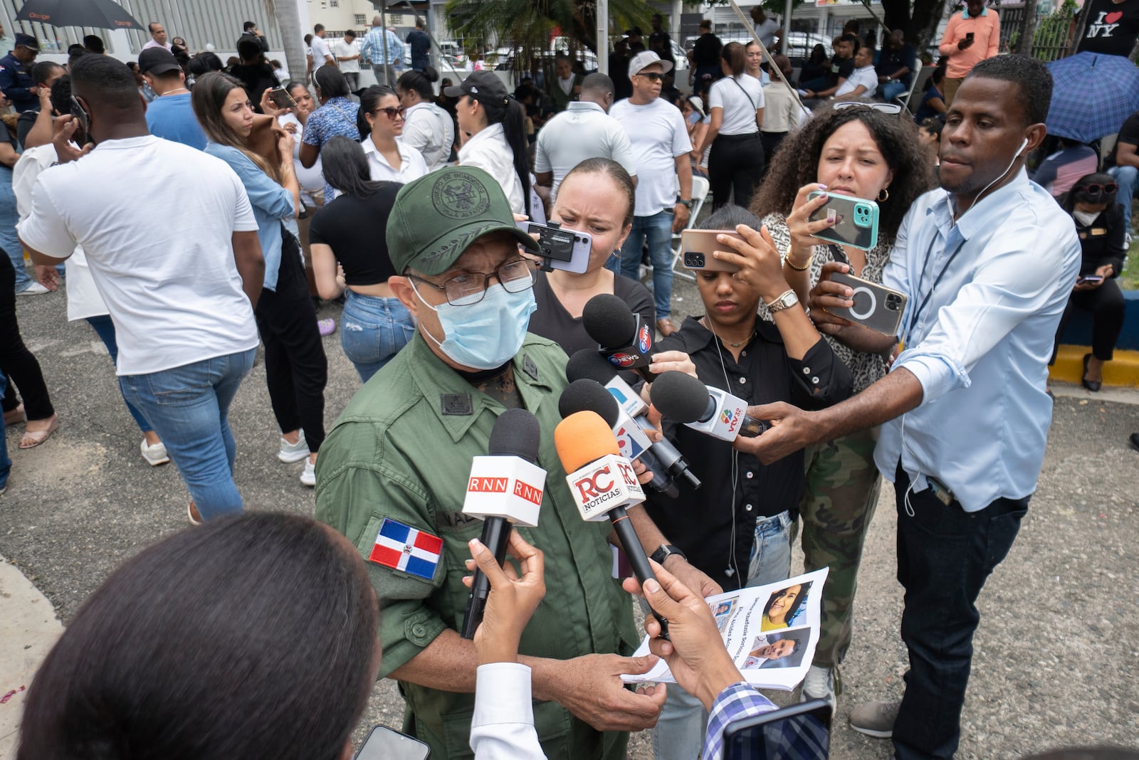 Colonel Valdez speaks to reporters at the National Institute of Forensic Pathology in Santo Domingo, Dominican Republic, Wednesday, April 9, 2025, while holding photos of people who remain missing after a roof collapsed at the Jet Set nightclub during a merengue concert. (AP Photo/Marvin Del Cid)