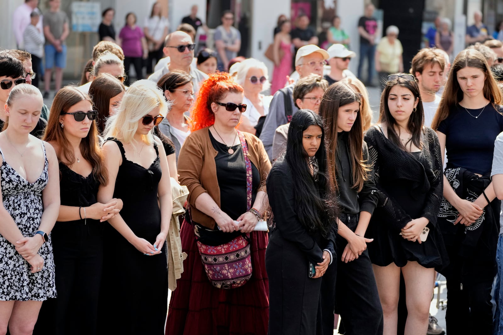 People pay a moment of silence on the main square after a former student opened fire the day before at a school fatally wounding several people and injuring many others before taking his own life, Graz, Austria, Wednesday, June 11, 2025. (AP Photo/Darko Bandic)