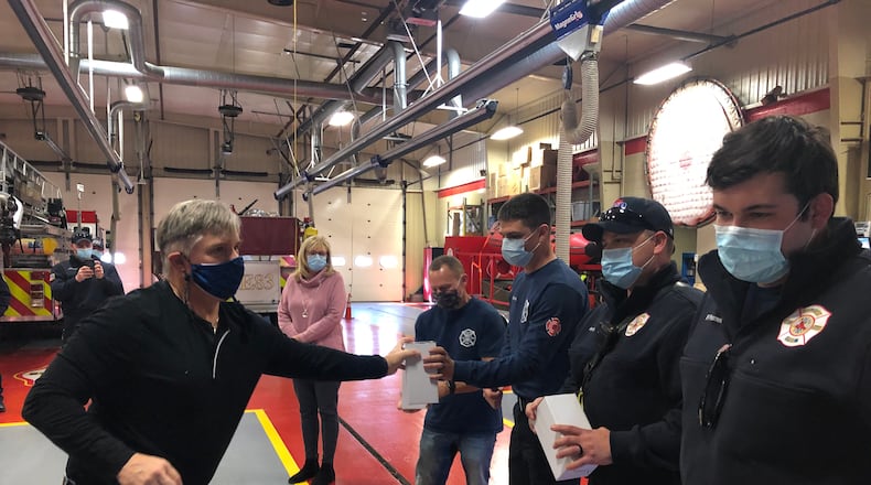Phil Keegan, 58, presents insulated tumblers to four of the five Middletown firefighters/paramedics who saved his life. RICK McCRABB/STAFF