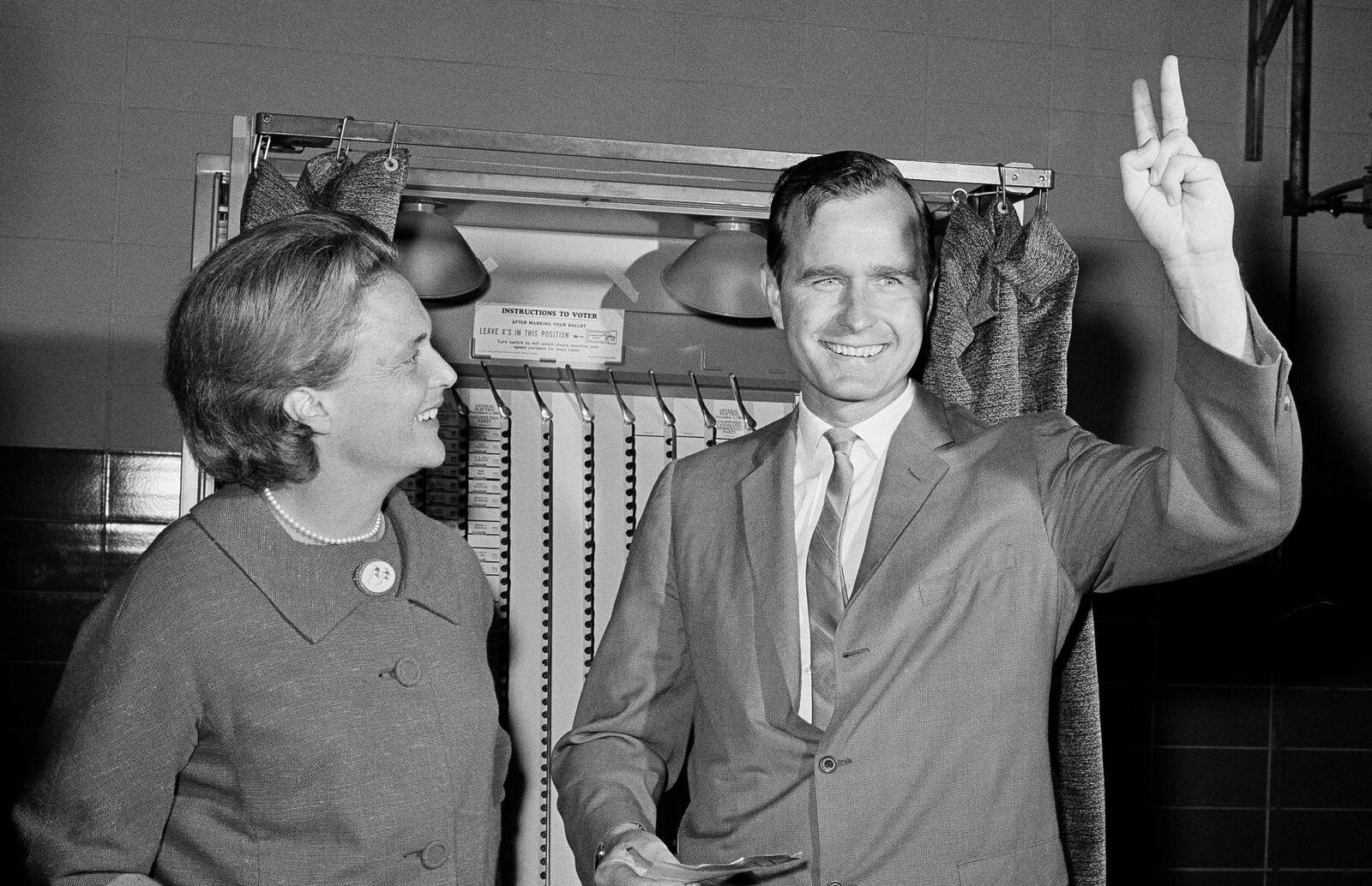 Republican Senatorial candidate George Bush shows a victory sign as he and his wife Barbara stand in front of a vote machine November 3, 1964 in Houston.