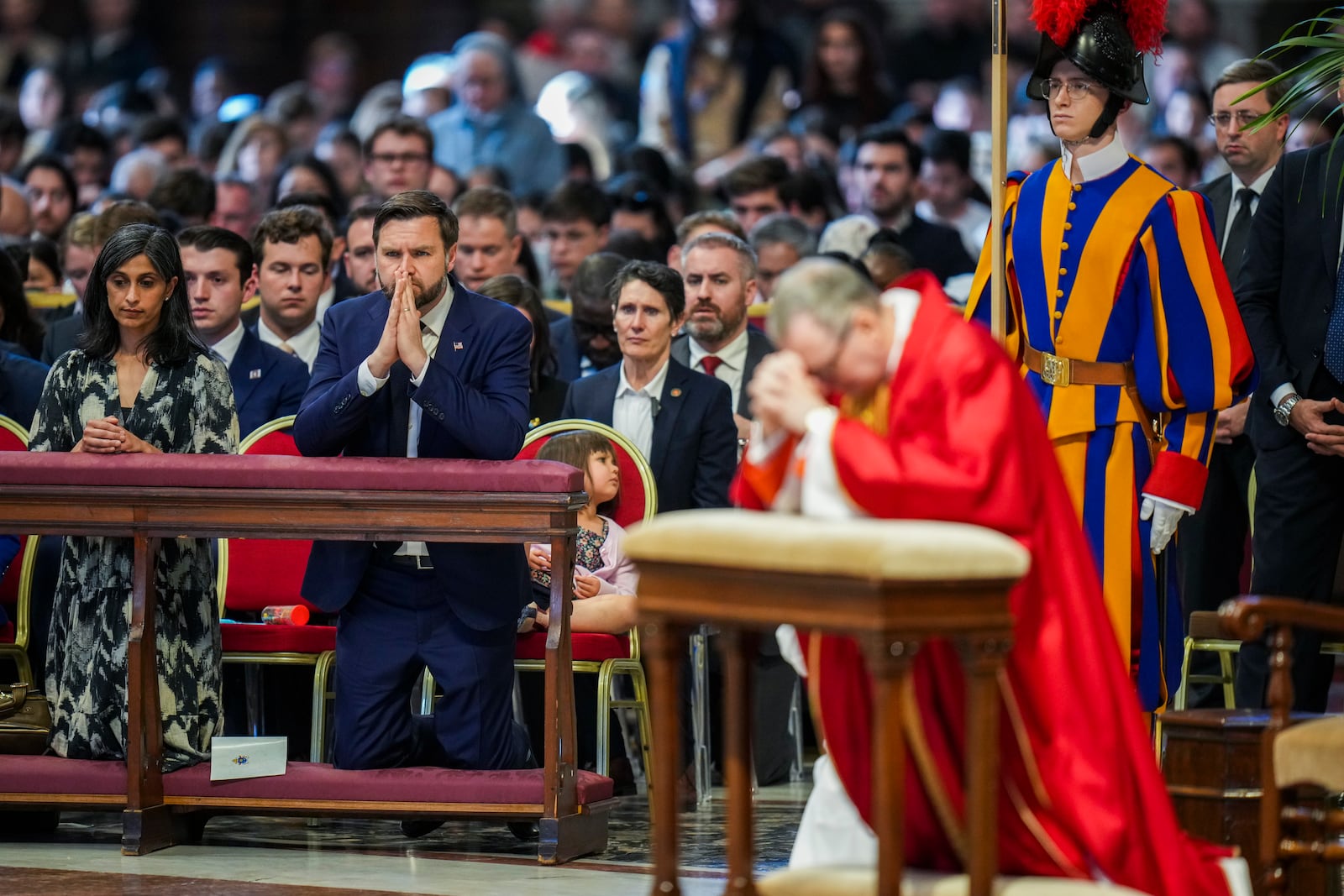 U.S. Vice President JD Vance, and his wife Usha Vance, left, with their daughter Mirabel attend a Good Friday service led by Cardinal Claudio Gugerotti, right, inside St. Peter's Basilica at the Vatican, Friday, April 18, 2025. (AP Photo/Alessandra Tarantino)