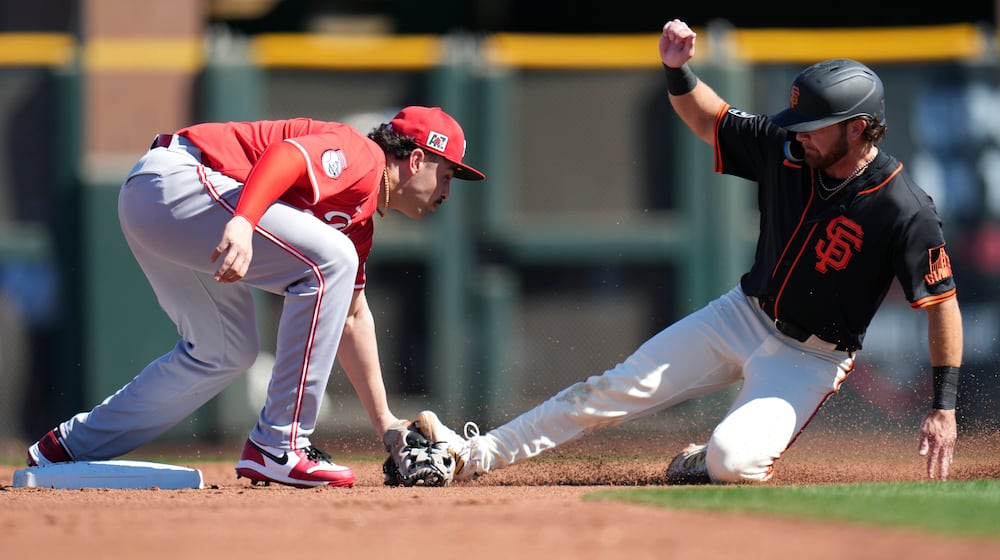 Cincinnati Reds infielder Sal Stewart, left, tags out San Francisco Giants' Brett Wisely, right, as Wisely tries to steal second during the second inning of a spring training baseball game Sunday, Feb. 23, 2025, in Scottsdale, Ariz. (AP Photo/Ross D. Franklin)