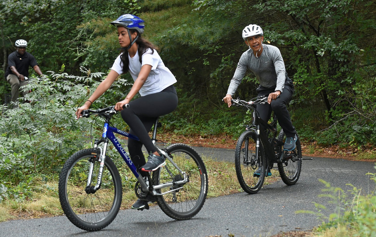 FILE - President Barack Obama follows his daughter Malia Obama as they rides bikes in West Tisbury, Mass., on Martha's Vineyard, Aug. 22, 2015, during the Obamas annual vacation. (AP Photo/Susan Walsh, File)