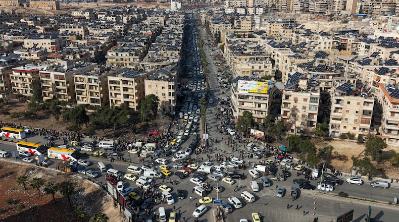 An aerial view shows Syrian residents in vehicles, queueing to flee from Sheikh Maqsoud and Achrafieh neighborhoods after clashes broke out on Tuesday between Syrian government forces and Kurdish fighters in a contested area of the northern city of Aleppo, Syria, Wednesday, Jan. 7, 2026. (AP Photo/Omar Albam)