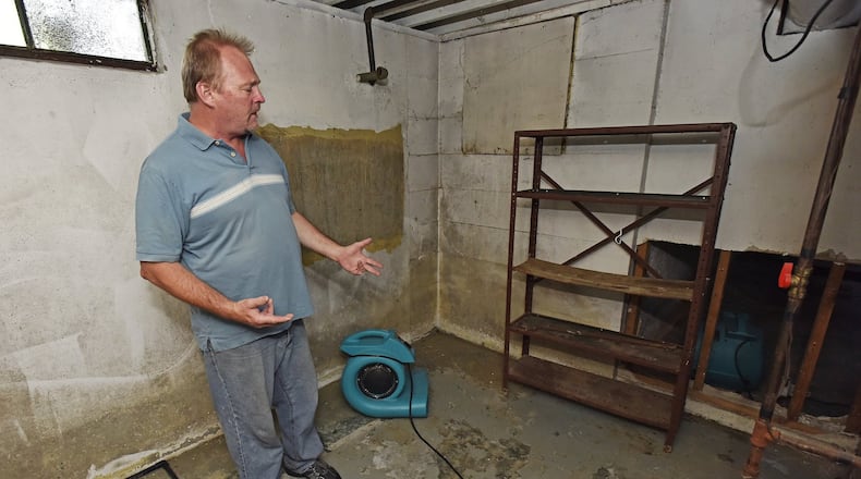 Mike Seeley stood in his Cereal Avenue basement in early June, several days after an intense rain flooded it. Much of the drywall that was soaked with water had been removed and he was using 10 industrial fans, a dehumidifier and an air cleaner to dry out the cellar. NICK GRAHAM/STAFF