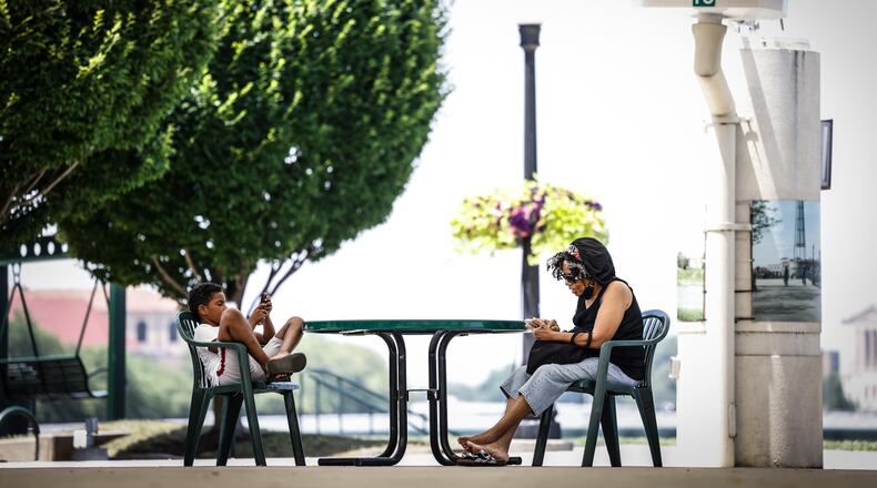 Jahleel Boyd and his grandmother, Sharon McGee enjoy some shade at RiverScape in downtown Dayton. McGee said they walked the river walk looking at the ducks and geese until they needed a break from the heat.  JIM NOELKER/STAFF