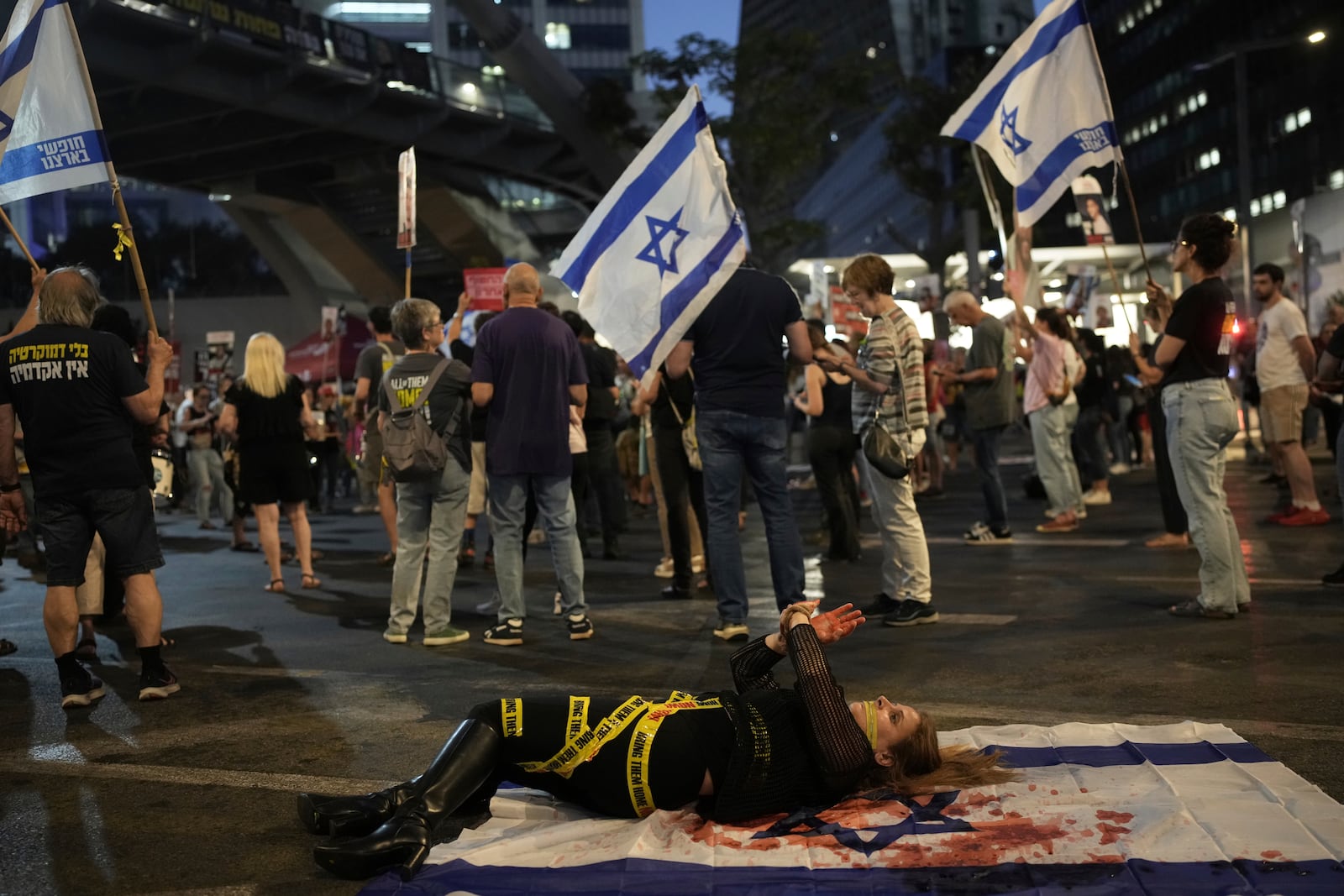 A demonstrator takes part in a performance during a protest against Prime Minister Benjamin Netanyahu's government and call for the release of hostages held in the Gaza Strip by the Hamas militant group, in Tel Aviv, Israel, Saturday, June 7, 2025. (AP Photo/Ohad Zwigenberg)