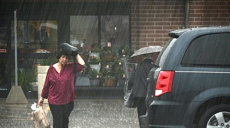 Shoppers make their way to their cars during heavy rainfall Wednesday April 5, 2023 at the Kroger marketplace in Beavercreek. MARSHALL GORBY \STAFF