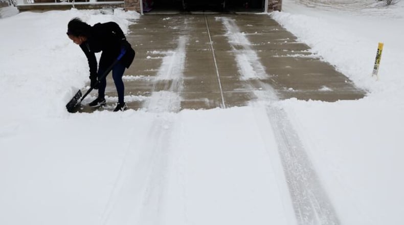 Shaquora Shelley cleans several inches of snow off her Huber Heights driveway Sunday, Feb. 16, 2025. BILL LACKEY/STAFF