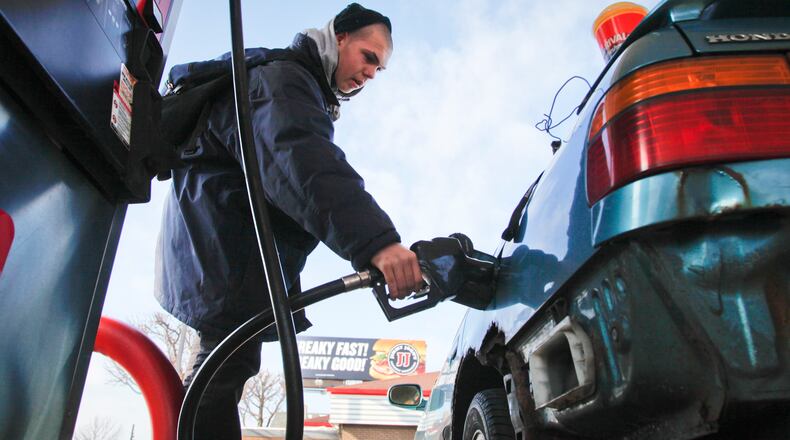 Gabriel Fletcher of Dayton pumps gas for his mother Jan 4, 2013 at a Dayton gas station. STAFF PHOTO BY LISA POWELL