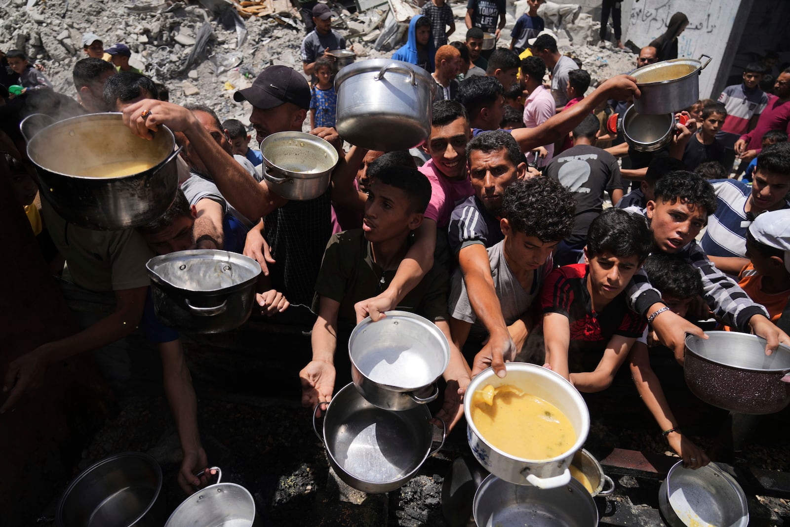 Palestinians struggle to get donated food at a community kitchen in Jabalia, northern Gaza Strip, Monday, May 19, 2025. (AP Photo/Jehad Alshrafi)