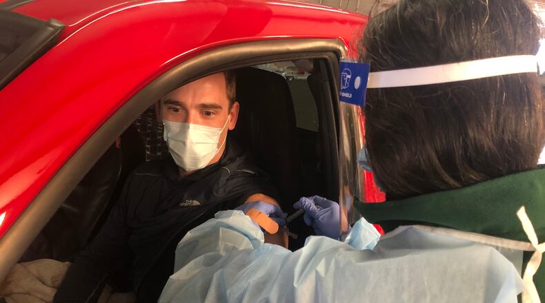 John Tranovich, a dental assistant in Monroe, receives a COVID-19 vaccine from Mita Patel, a registered nurse with the Butler County General Health District, Friday morning during a drive-through vaccination at the Butler County Fairgrounds. RICK McCRABB/STAFF