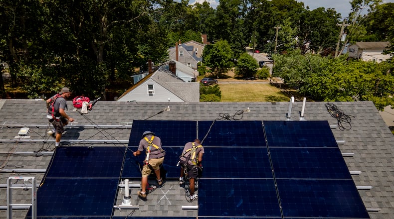 The city of Springboro amended its planning and zoning code to make it easier for residents and businesses to install solar panels on their homes and structure. This file photo shows a company installing an array of solar panels on a roof in Massapequa, N.Y. last month. (AP Photo/John Minchillo)