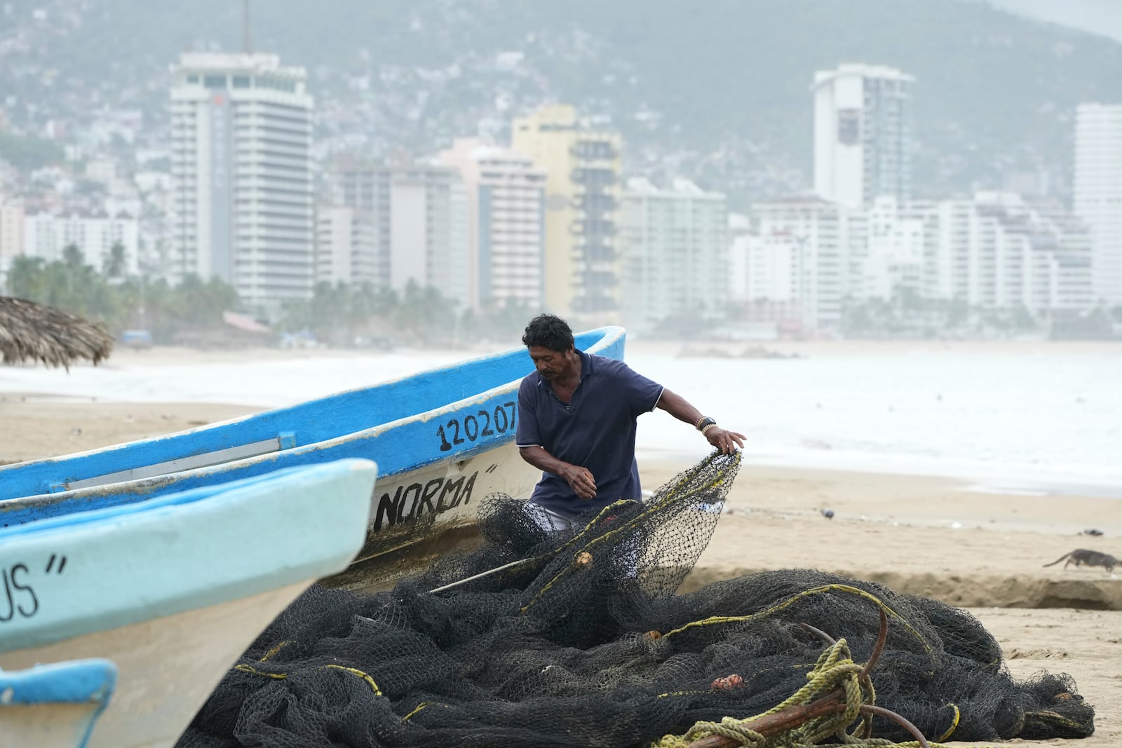A fisherman maintains his net while his boat is off the water on Manzanillo beach as Hurricane Erick passes near Acapulco, Mexico, Thursday, June 19, 2025. (AP Photo/Fernando Llano)