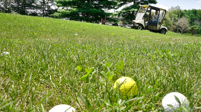 The tall grass makes it hard for a grounds keeper to pick up the balls on the driving range at Locust Hills Golf Course Thursday. Bill Lackey/Staff
