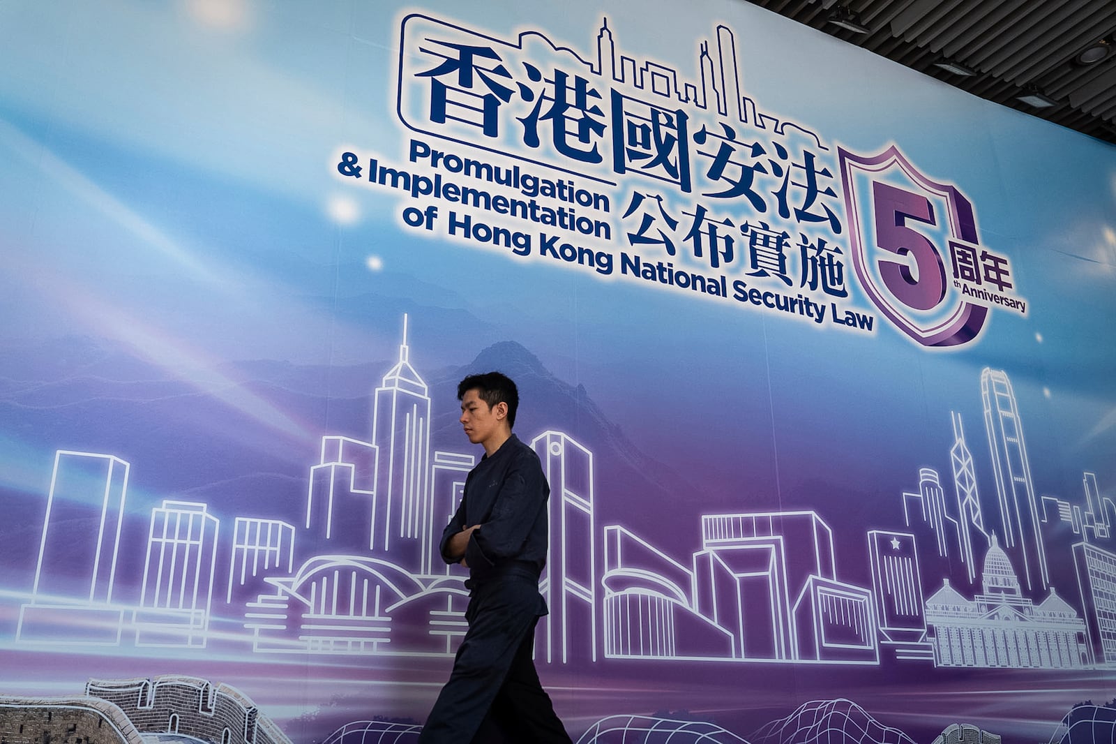 A pedestrian walks past a banner celebrating the 5th Anniversary of the implementation of Hong Kong National Security Law in Hong Kong, Saturday, June 21, 2025. (AP Photo/Chan Long Hei)
