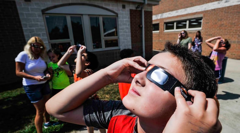 Joel Bramblett, 11, a fifth grade student at Lakota's Endeavor Elementary School, views the solar eclipse through approved solar glasses Monday, Aug. 21 in West Chester Township. NICK GRAHAM/STAFF