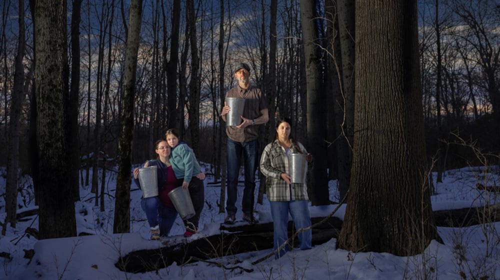 Kristina and Adeline Fox, George Ironstrack and Kara Strass of the Miami Tribe of Oklahoma among Black Maples in Oxford, holding buckets used to gather sap from surrounding maple trees. Photo by Tina Gutierrez, 2025. CONTRIBUTED