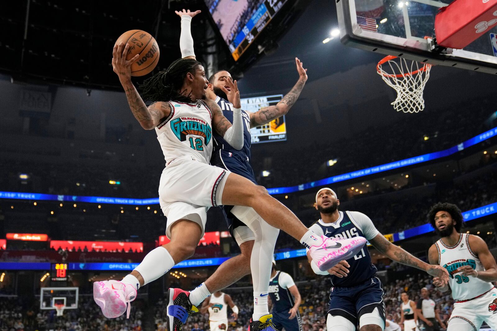Memphis Grizzlies guard Ja Morant (12)- passes the ball around Dallas Mavericks forward Caleb Martin, right, during the first half of an NBA play-in tournament basketball game Friday, April 18, 2025, in Memphis, Tenn. (AP Photo/George Walker IV)
