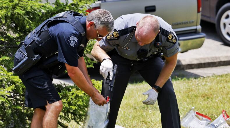Police place a gun found in a grassy area of an apartment complex into an evidence bag Wednesday, June 22, 2022, in Springboro following a chase that began in Franklin. NICK GRAHAM/STAFF