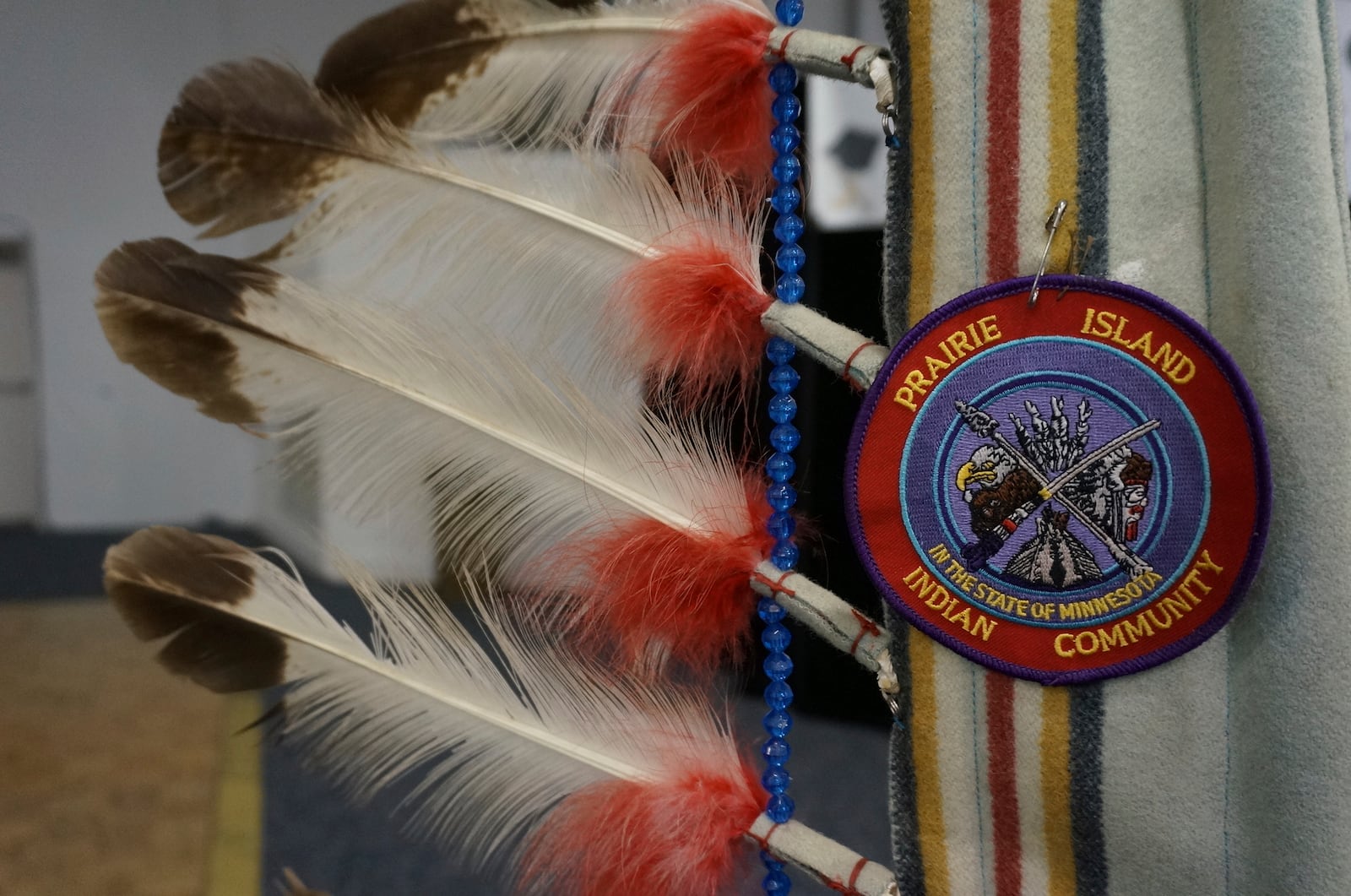 A ceremonial staff with eagle feathers stands near the podium at a ceremony honoring high school and higher education graduates at the Prairie Island Indian Community in Minnesota on Wednesday, July 9, 2025. (AP Photo/Giovanna Dell'Orto)