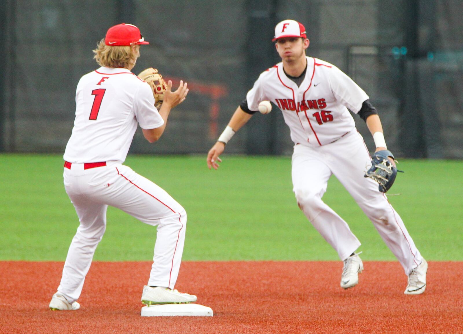 Fairfield infielders Cameron Tenhundfeld (1) and Kaleb Ford (16) flip for a force out at second base during their Division I regional semifinal against St. Xavier on Thursday at the University of Cincinnati’s Marge Schott Stadium. GREG LYNCH/STAFF
