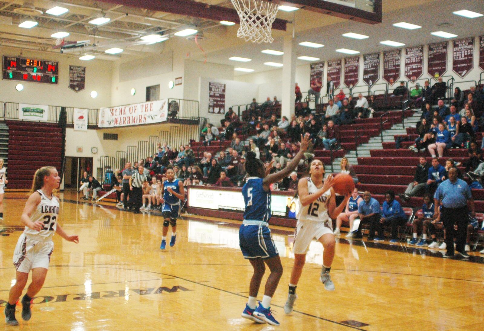 Lebanon’s Kendall Folley (12) drives to the basket as Hamilton’s Leah Smith (5) defends Nov. 26, 2018, at LHS. That’s the Warriors’ Logan Mueller (22) watching the play. Visiting Big Blue secured a 52-42 triumph. RICK CASSANO/STAFF