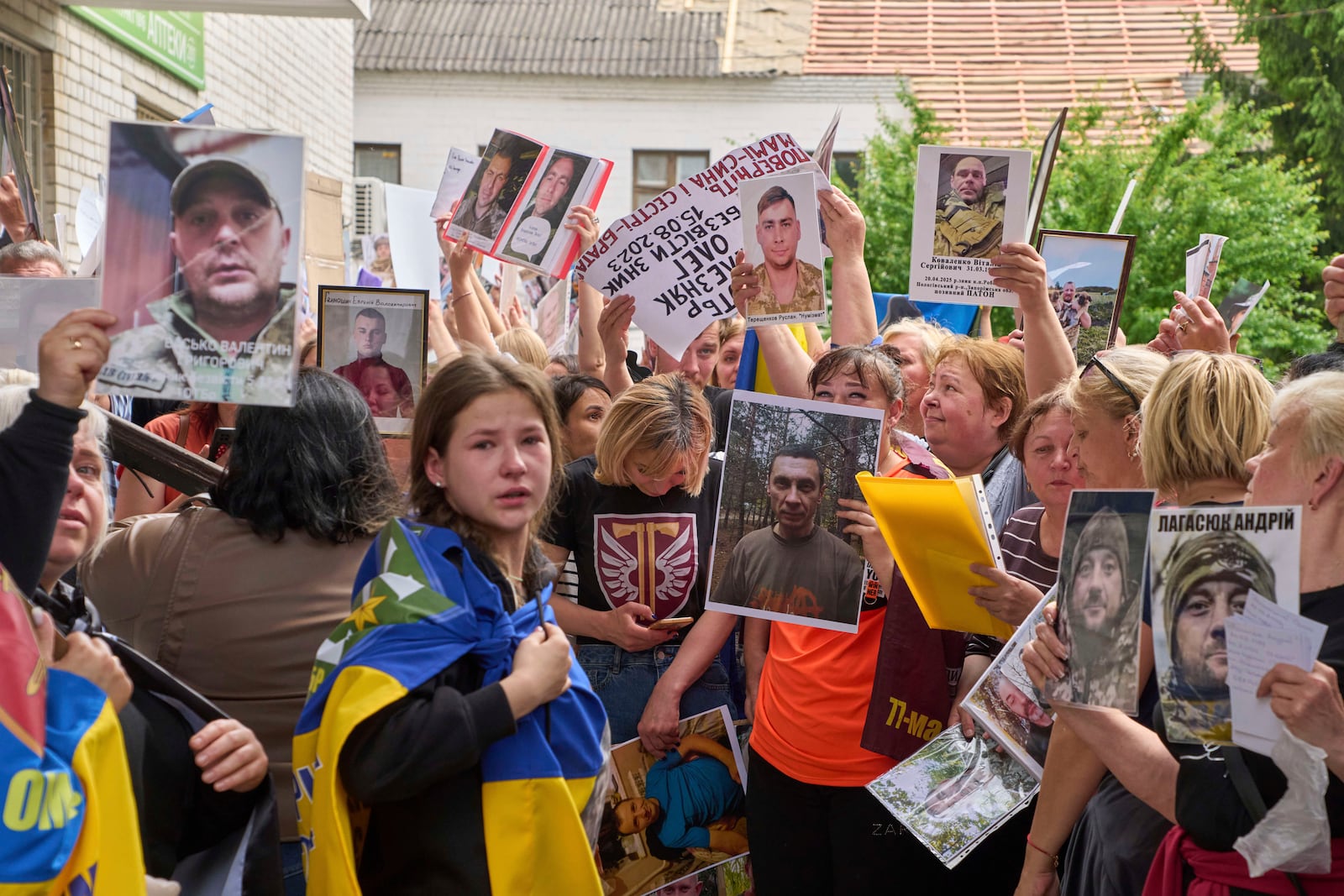 Relatives show photos of missing soldiers to POWs who came back from Russian captivity during an exchange of prisoners between Russia and Ukraine, in Chernyhiv region, Ukraine, Sunday, May 25, 2025. (AP Photo/Efrem Lukatsky)