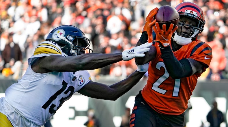 Cincinnati Bengals cornerback Mike Hilton (21) makes an interception of a pass intended for Pittsburgh Steelers wide receiver James Washington (13) during the first half of an NFL football game, Sunday, Nov. 28, 2021, in Cincinnati. Hilton returned the ball for a touchdown. (AP Photo/Jeff Dean)
