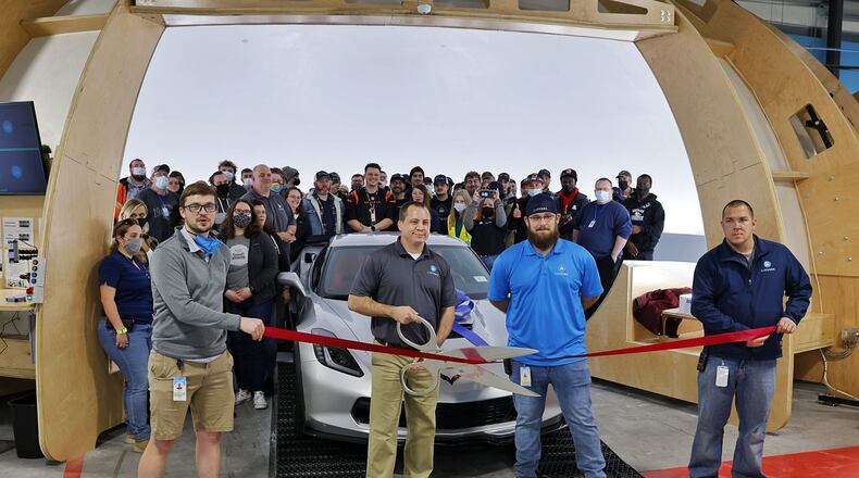 Carvana, an automotive processing facility at 5506 Kennel Road in Trenton, held its ribbon-cutting Friday afternoon. General manager Justin Nelsen holds the scissors while associates stand in a large area when the cars are photographed. NICK GRAHAM/STAFF