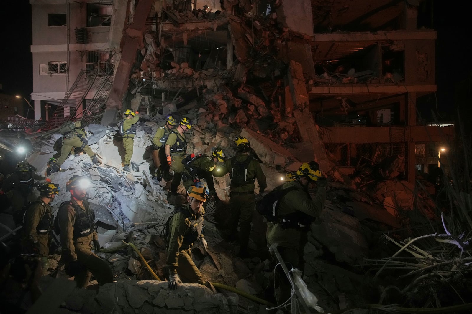 Israeli security forces inspect destroyed buildings that were hit by a missile fired from Iran, near Tel Aviv, Israel, Sunday, June 15, 2025. (AP Photo/Ohad Zwigenberg)
