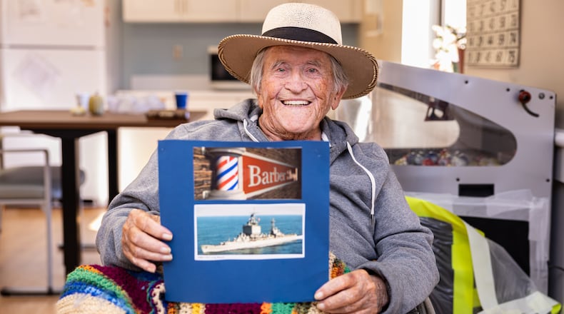 Paul Hughes poses with pictures on Thursday, Nov. 6 at Community Living Center on the VA campus in Dayton. Hughes served in the Navy for about 20 years and worked primarily as a barber while deployed in a destroyer. After retiring from the Navy, he worked as a barber in Dayton. BRYANT BILLING/STAFF