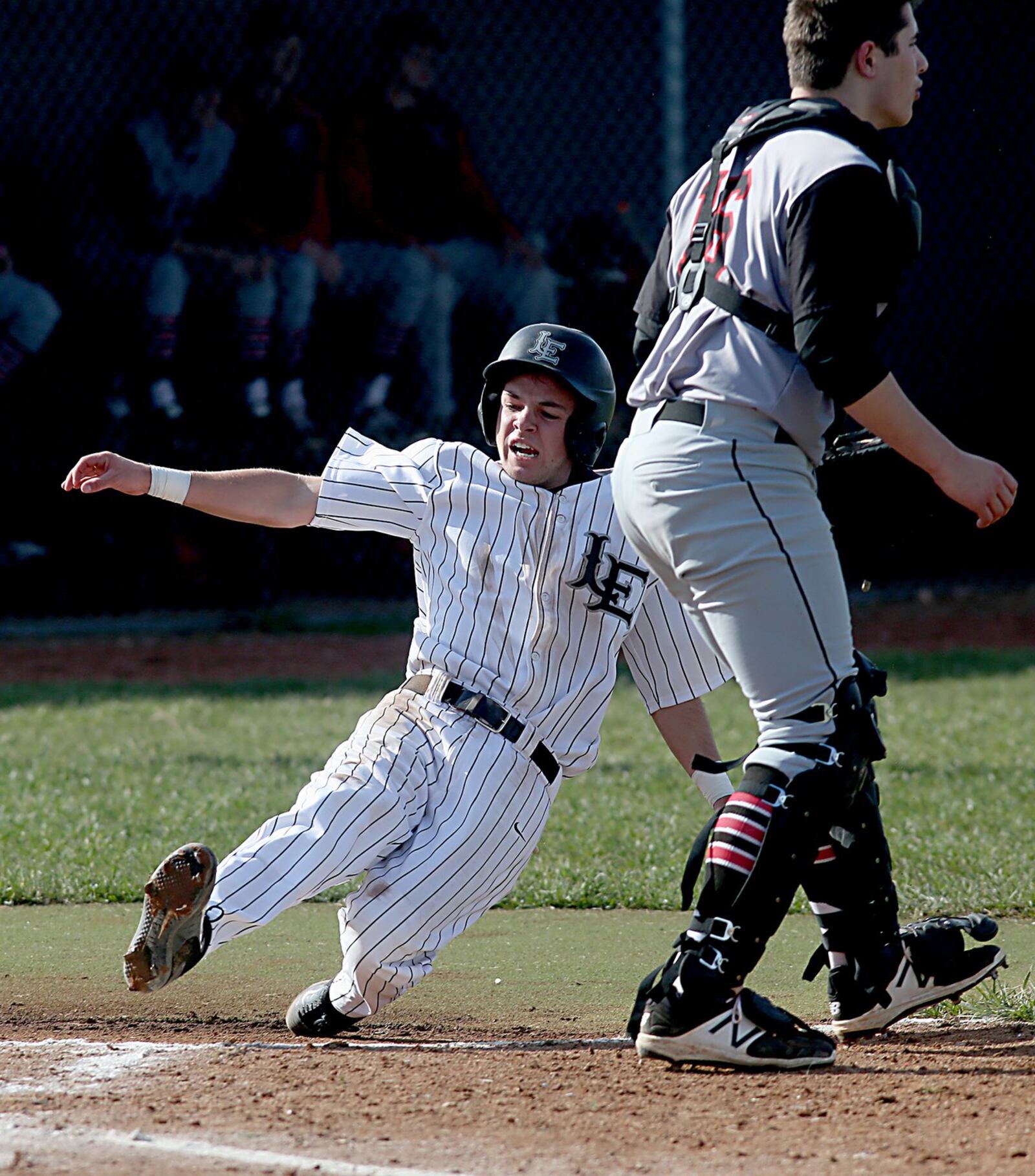 Noah Smith scores Lakota East’s first run as Oak Hills catcher Brett Kron waits for a throw during Tuesday’s game at East. CONTRIBUTED PHOTO BY E.L. HUBBARD