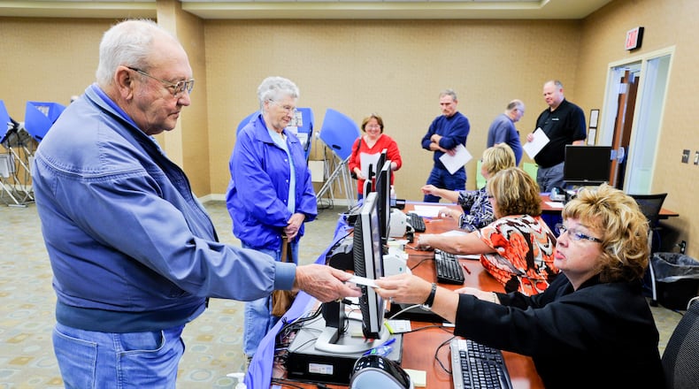 Donna Defazio hands a voting card to Marion Mink during the first day of early voting in 2012 in Butler County. Defazio, who worked for the Butler County Board of Elections for 10 years, died Monday. She was 63. NICK GRAHAM/2012