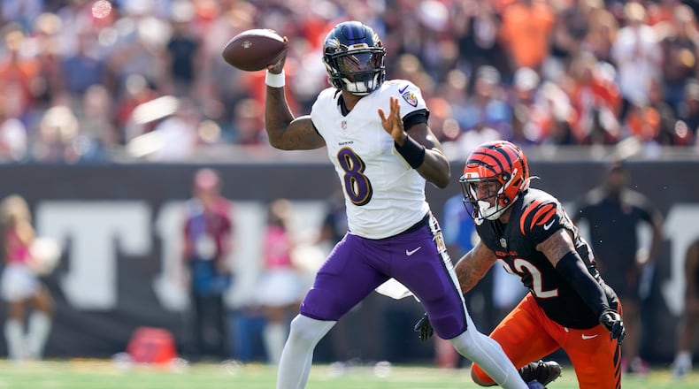 Baltimore Ravens quarterback Lamar Jackson, left, attempts a pass as Cincinnati Bengals safety Geno Stone (22) applies pressure during the first half of an NFL football game, Sunday, Oct. 6, 2024, in Cincinnati. (AP Photo/Carolyn Kaster)