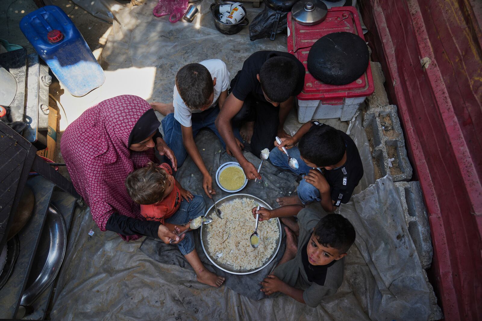 Tahreer Abu Jazar, 36, shares an Eid al-Adha meal of lentil soup and rice with her children inside their tent at a camp for displaced Palestinians in Mawasi Khan Younis, Gaza Strip, on Friday, June 6, 2025. (AP Photo/Abdel Kareem Hana)
