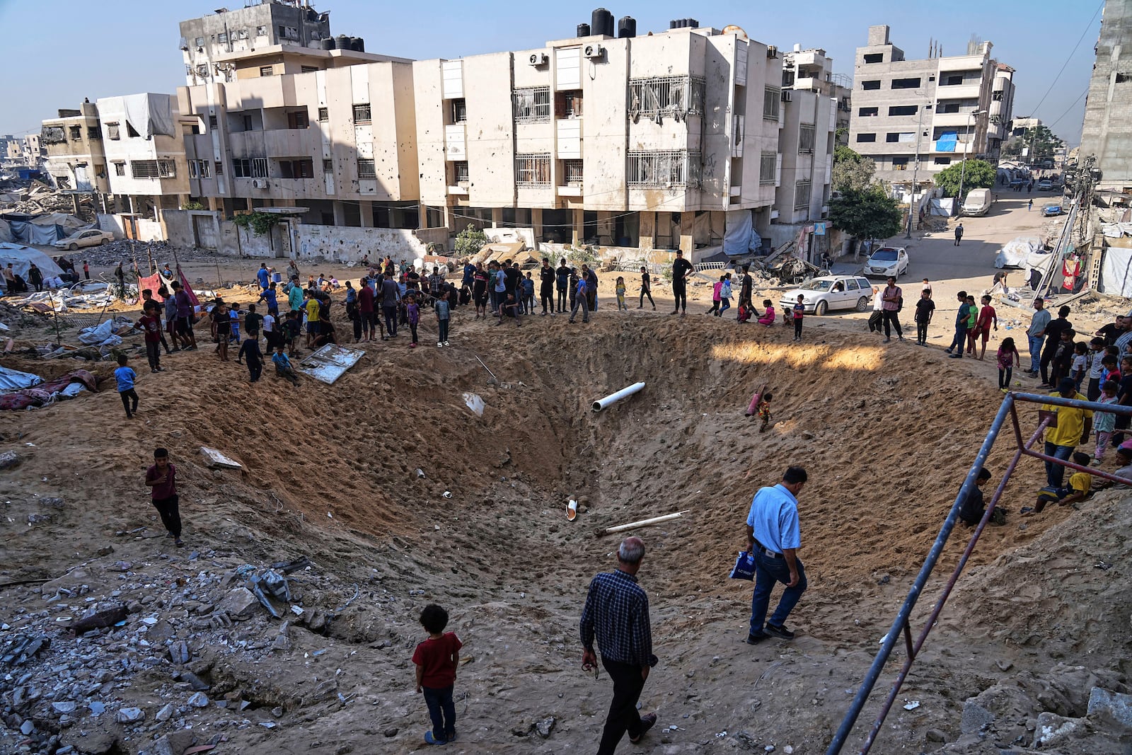 Palestinians gather around a crater caused by an Israeli strike on a displacement tent camp in Gaza City, June 28, 2025. (AP Photo/Jehad Alshrafi)